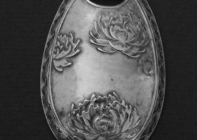 Gravure en volume de pivoines avec, en fond, une structure figurant des nuages. Sur le tour, décor répétitif en gravure taille douce.