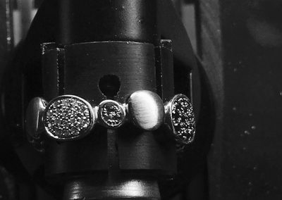 bague en forme de petits galets sertie de diamants blancs, noirs et d'émeraudes.