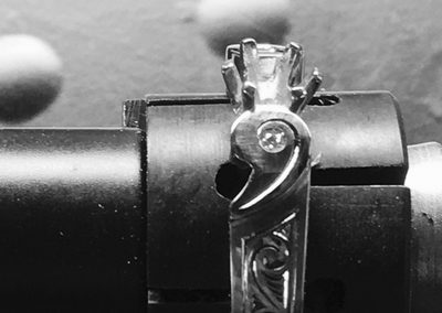 bague serte d'un diamant serti griffe, d'un clos de chaque côté et décorée de volutes gravées sur les côtés.