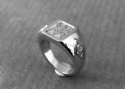 chevalière avec des armoiries sur le dessus et 5 diamants sertis de chaque côté.