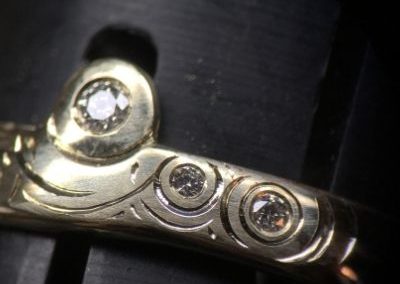 Bague en or sertie de diamants avec des traits gravés autour représentant de l'eau.