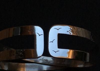 bracelet gravé de petits oiseau à l'extérieure d'une longue phrase à l'intérieur.